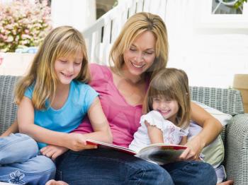 Royalty Free Photo of a Woman and Two Girls Reading Outside