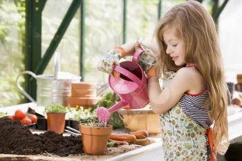 Royalty Free Photo of a Young Girl Watering a Plant