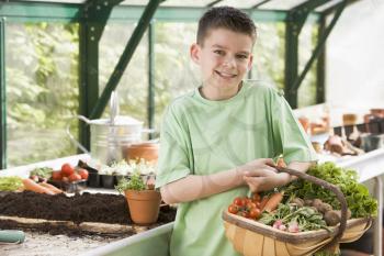 Royalty Free Photo of a Young Boy in a Greenhouse With Vegetables