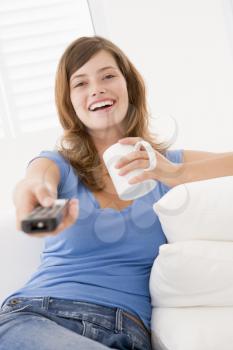 Royalty Free Photo of a Woman With a Remote Control and a Coffee