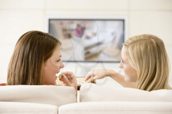 Royalty Free Photo of Two Women Watching TV and Eating Chocolate
