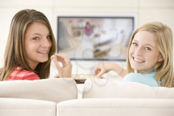 Royalty Free Photo of Two Girls Eating Chocolate and Watching Television