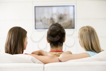Royalty Free Photo of a Guy and Two Girls Watching Television