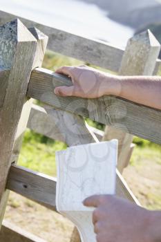 Royalty Free Photo of a Man's Hand Holding a Fence and a Map