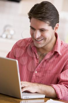Royalty Free Photo of a Man Using a Laptop in a Kitchen