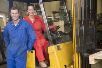 Royalty Free Photo of Two Warehouse Workers Beside a Forklift