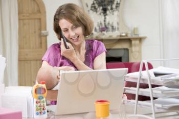 Royalty Free Photo of a Woman Talking on the Phone While Holding a Baby