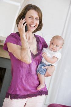 Royalty Free Photo of a Mother Talking on a Phone and Holding a Baby