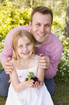 Royalty Free Photo of a Father and Daughter Holding a Plant
