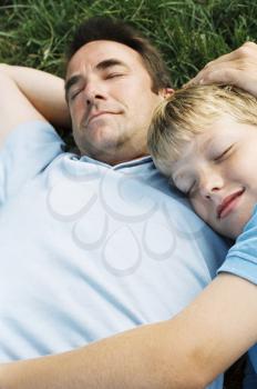 Royalty Free Photo of a Father and Son Sleeping on the Lawn