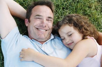 Royalty Free Photo of a Father and Daughter Asleep on the Lawn