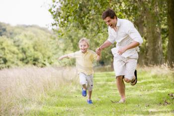 Royalty Free Photo of a Father and Son Running in a Park