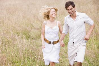 Royalty Free Photo of a Couple Running in a Field