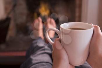 Royalty Free Photo of a Person Having a Hot Drink by a Fire