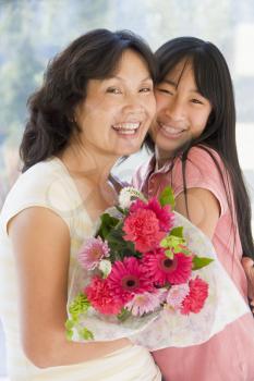 Royalty Free Photo of a Girl Giving a Woman Flowers and a Hug