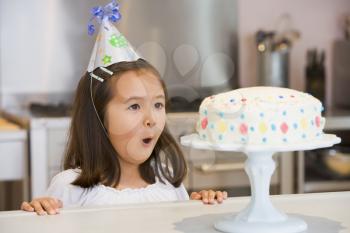 Royalty Free Photo of a Girl in a Birthday Hat at the Kitchen Counter