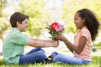 Royalty Free Clipart Image of a Little Boy Giving a Girl Flowers