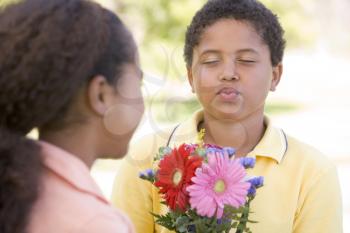 Royalty Free Photo of a Boy Giving a Girl Flowers and Puckering Up