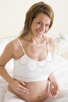 Royalty Free Photo of a Pregnant Woman Rubbing Cream on Her Belly