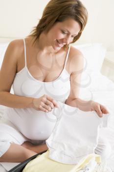 Royalty Free Photo of a Pregnant Woman Looking at Baby Clothes