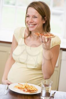 Royalty Free Photo of a Pregnant Woman Eating Pizza and French Fries