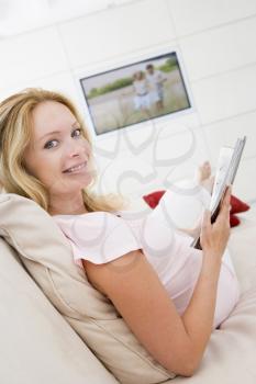 Royalty Free Photo of a Pregnant Woman in Front of a TV Reading a Book