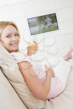 Royalty Free Photo of a Pregnant Woman Drinking Wine in Front of the TV