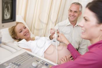 Royalty Free Photo of a Woman Getting an Ultrasound With Her Husband Watching