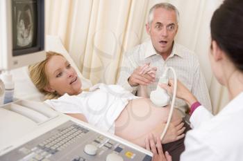Royalty Free Photo of a Woman Having an Ultrasound and Her Husband Looking Surprised