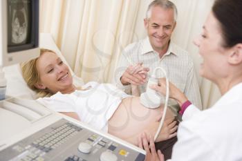 Royalty Free Photo of a Woman Having an Ultrasound and Her Husband Watching