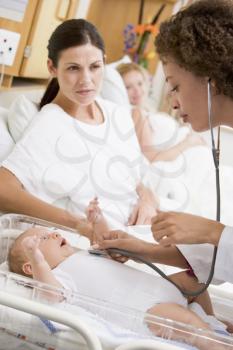 Royalty Free Photo of a Doctor Checking a Baby's Heartbeat and Looking Worried