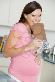 Royalty Free Photo of a Pregnant Woman Taking a Bite Out of a Chocolate Bar
