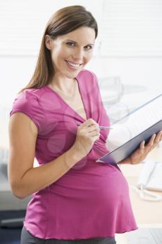 Royalty Free Photo of a Pregnant Woman Writing in a Binder