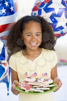 Royalty Free Photo of a Girl With a Plate of Cookies With American Flags on Them