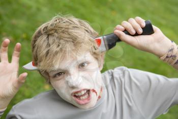 Royalty Free Photo of a Boy With a Scary Halloween Knife in His Head