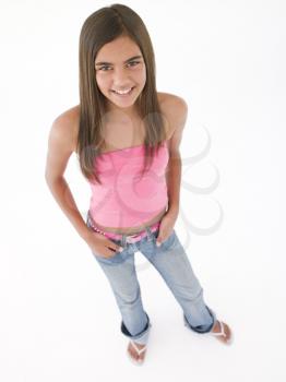 Young girl standing with hands in pockets smiling