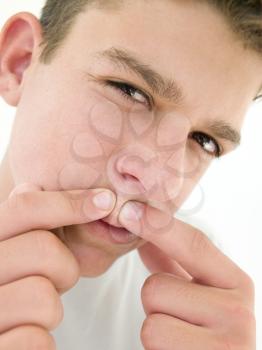 Royalty Free Photo of a Boy Squeezing a Pimple
