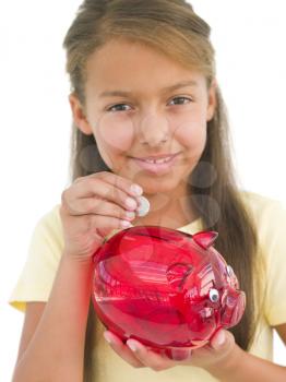 Royalty Free Photo of a Girl Putting Money in a Piggy Bank