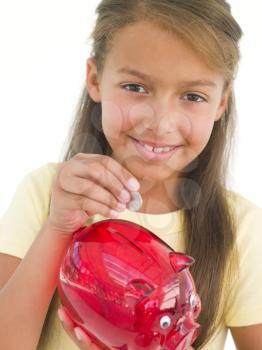 Royalty Free Photo of a Girl Putting Money in Her Piggy Bank