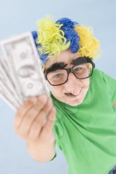 Royalty Free Photo of a Young Boy in a Clown Wig, Glasses and a Nose Holding Money