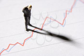 Royalty Free Photo of a Businessman Figurine Looking at a Graph