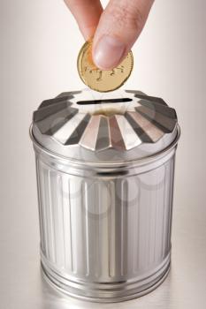Royalty Free Photo of a Coin Going Into a Trash Bin Bank