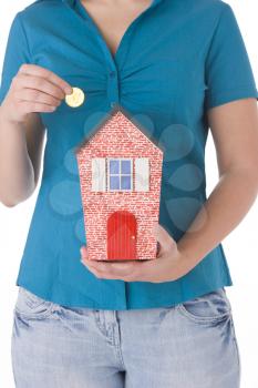 Royalty Free Photo of a Woman Putting Money in a House Bank