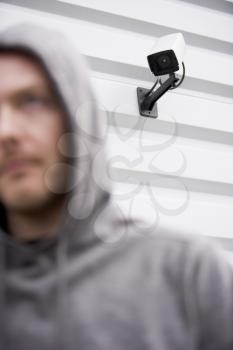 Royalty Free Photo of a Surveillance Camera and a Young Man in a Hoodie