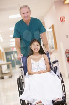 Royalty Free Photo of an Orderly Pushing a Girl in a Wheelchair