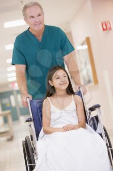 Royalty Free Photo of an Orderly Pushing a Little Girl in a Wheelchair