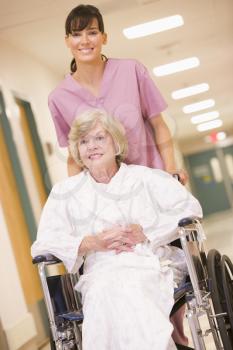 Royalty Free Photo of a Nurse Pushing a Woman in a Wheelchair
