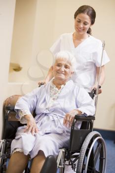 Royalty Free Photo of a Nurse Pushing a Woman in a Wheelchair