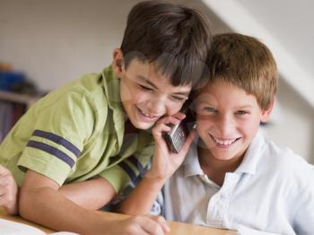 Royalty Free Photo of Two Boys Calling Someone on a Cellphone