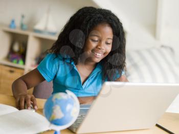 Royalty Free Photo of a Girl Doing Homework With a Laptop